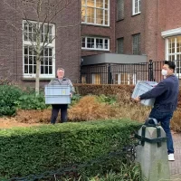Bart Ankersmit (RCE) en Seojin Kim (RCE) brengen containers met testboeken naar de Ateliergebouw in Amsterdam.
